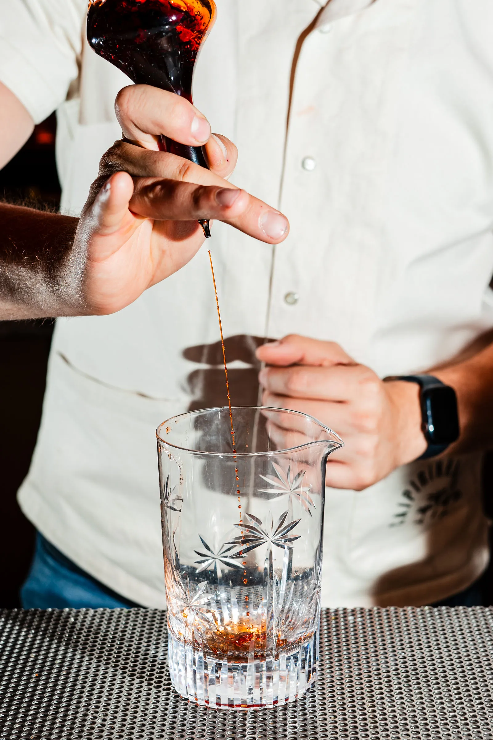 A CANA bartender preparing a cocktail behind the bar.