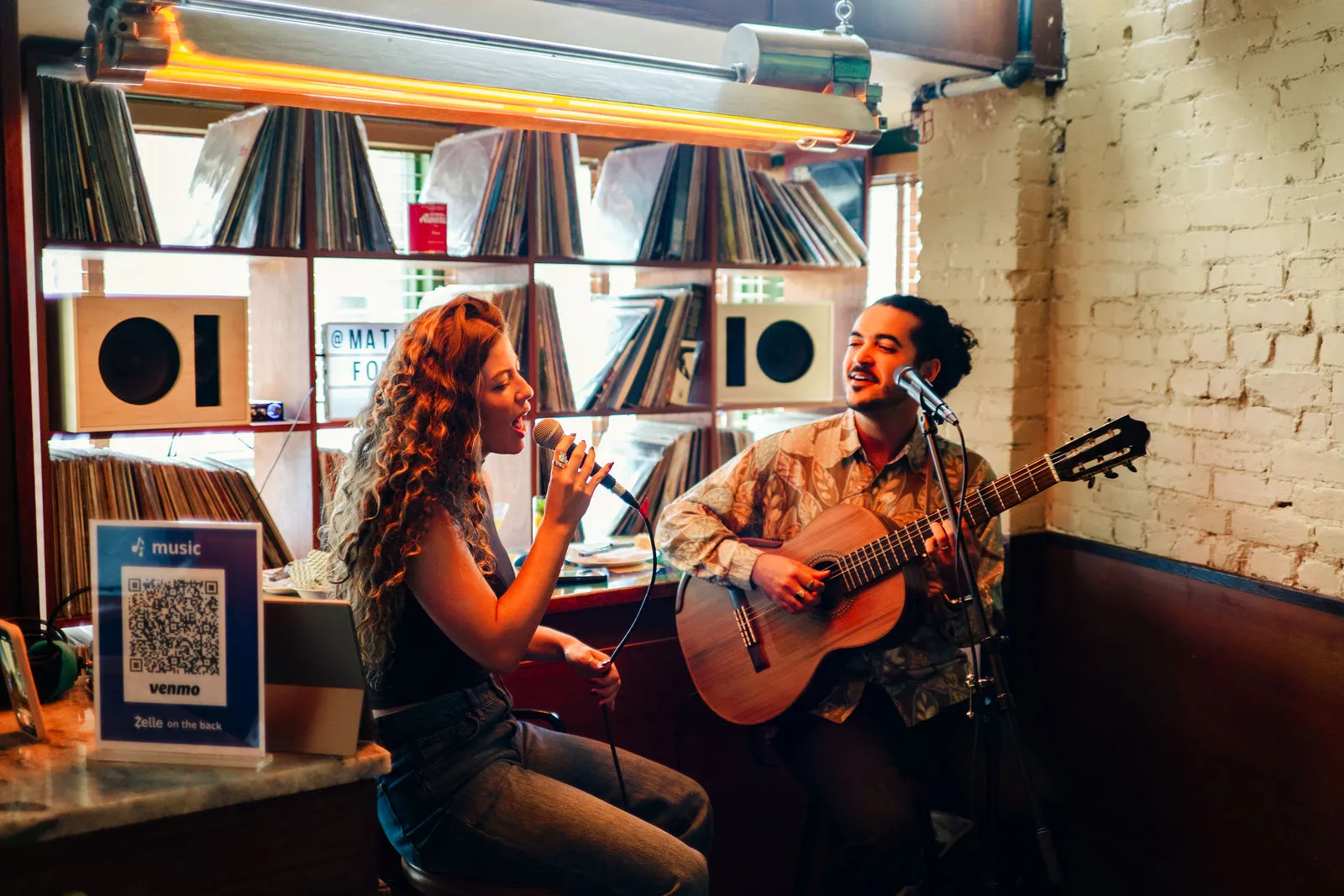 A vocalist and guitarist performing in front of CANA's record wall