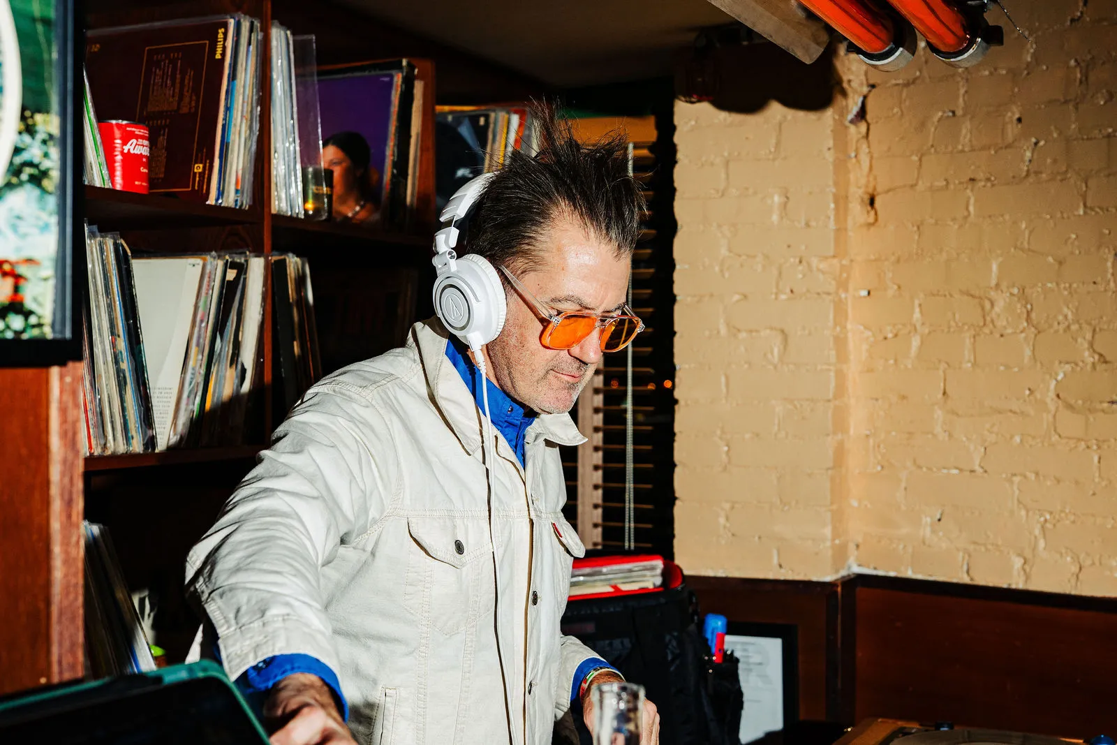 A DJ in orange glasses wearing headphones at CANA