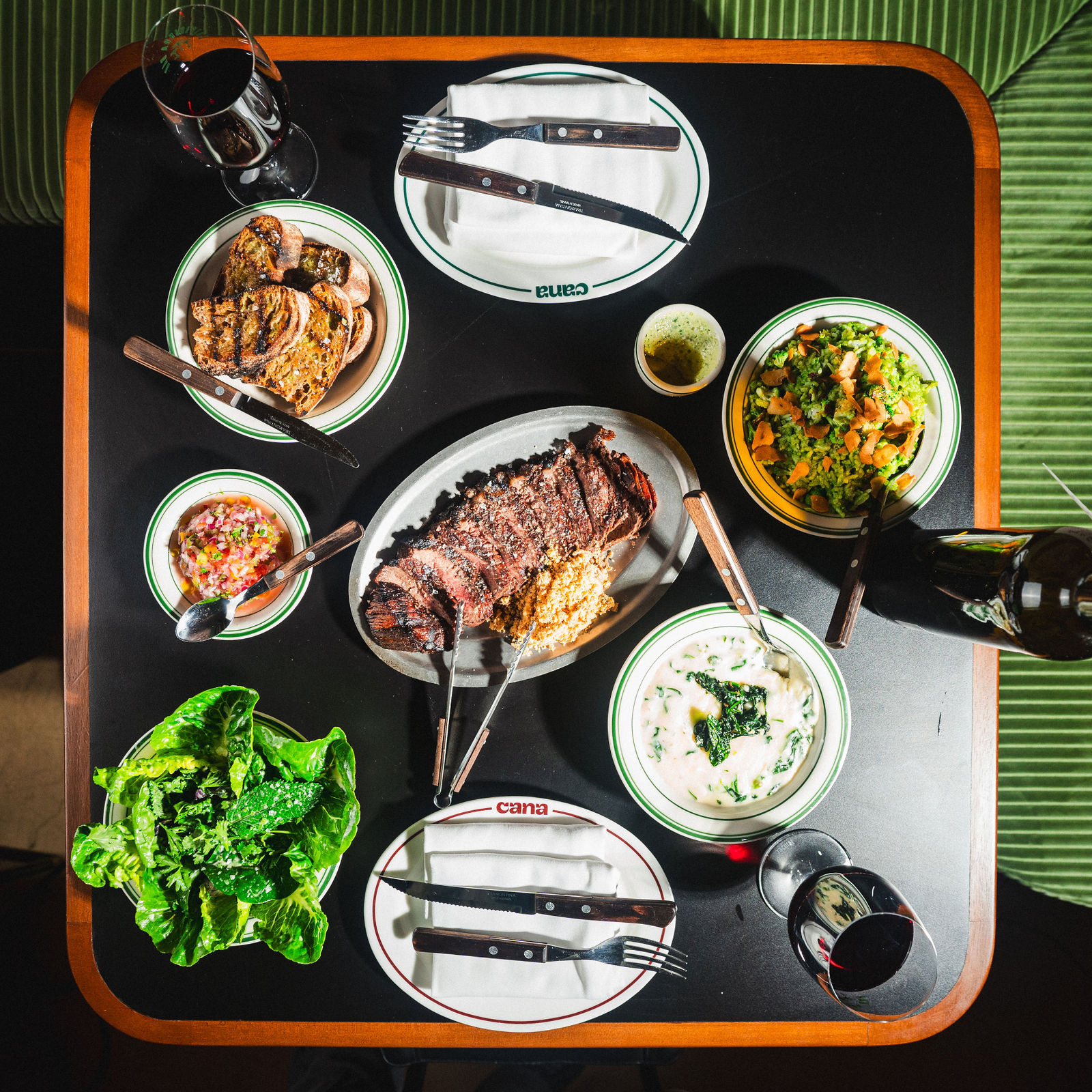 Overhead table spread with picanha, small plates, and drinks at CANA