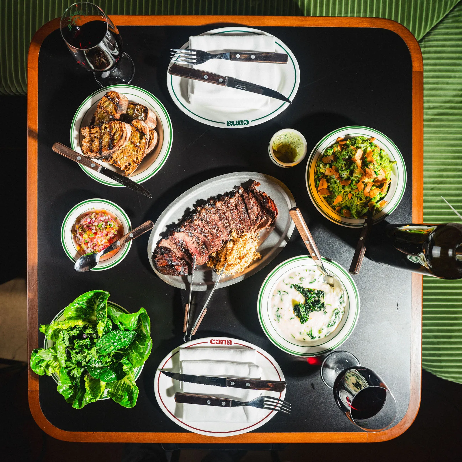 Overhead table spread with picanha, small plates, and drinks at CANA