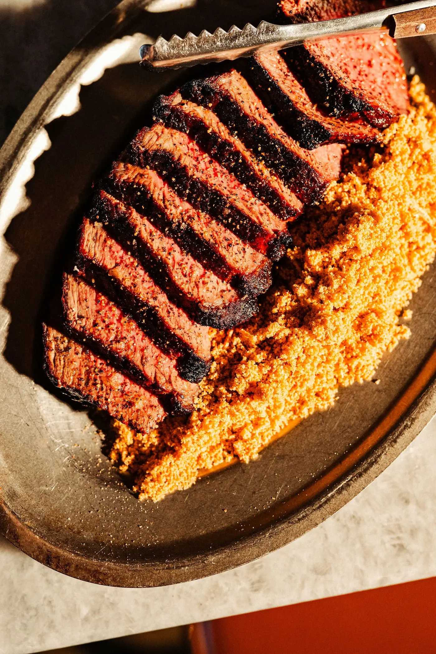 Sliced picanha on the churrasco board at CANA