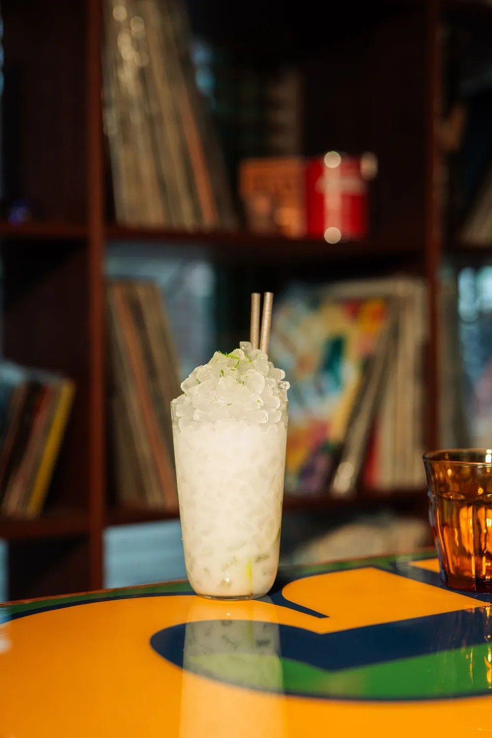 A caipirinha at Cana with records on the shelf behind it