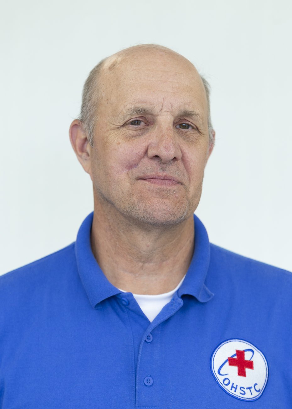 Man with short gray hair wearing blue polo with OHSTC red cross logo on chest.