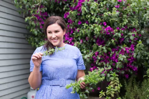 Jess's Underground Kitchen owner in garden picking rosemary