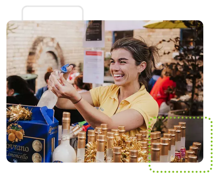 Limoncello salesperson offering taste testers at farmers market