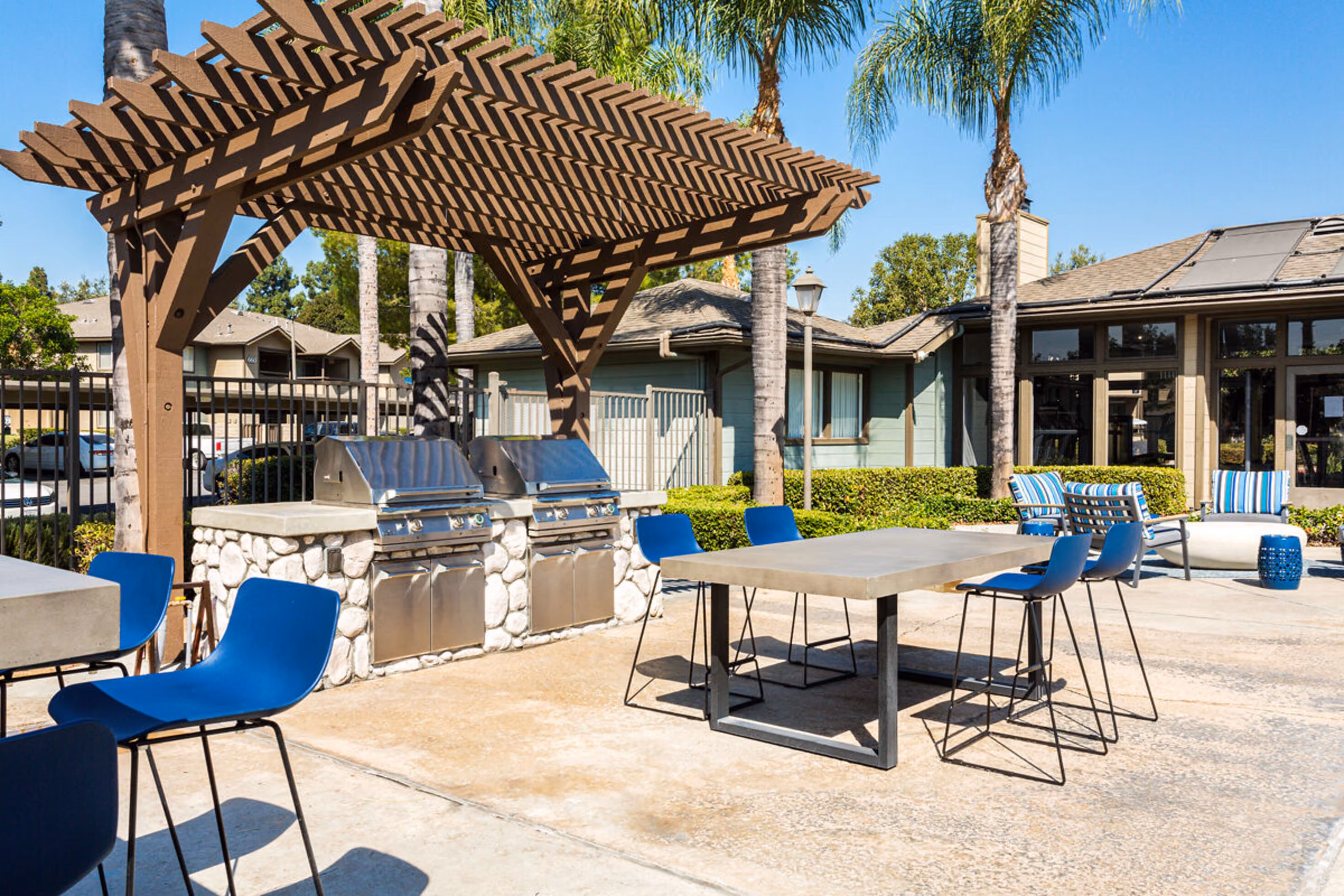 Pool with lounge chairs surrounding on the deck and bbq grills