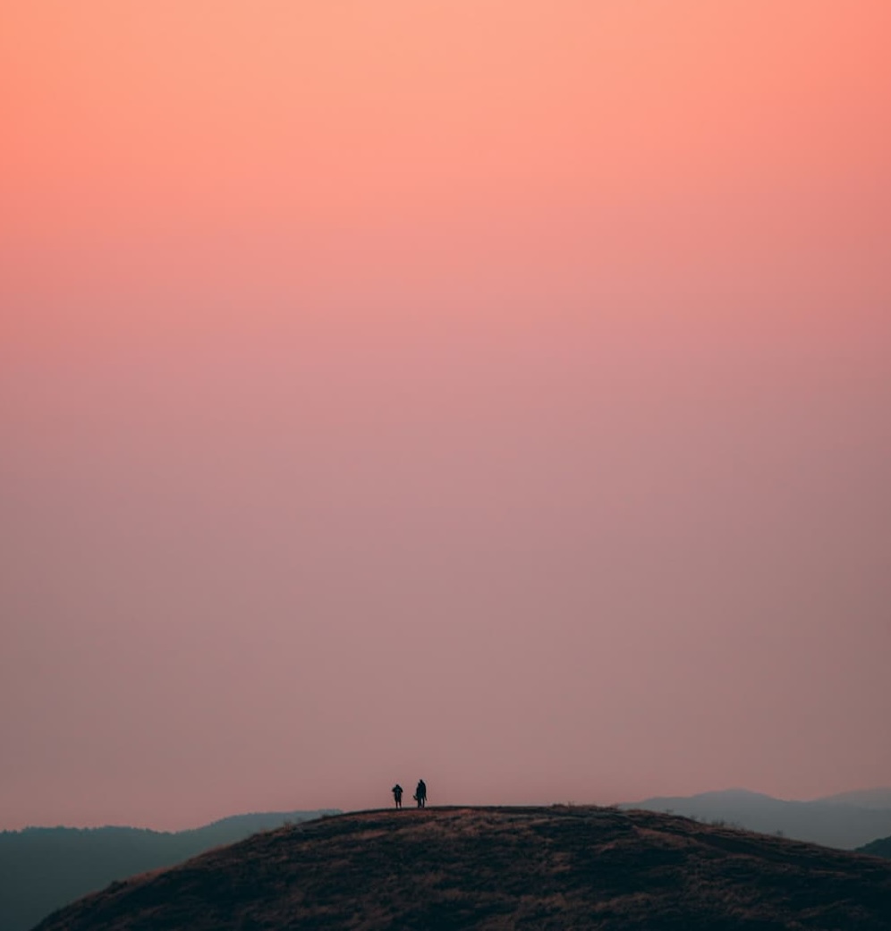 Two people on a hilltop at sunset, symbolizing support on your health journey