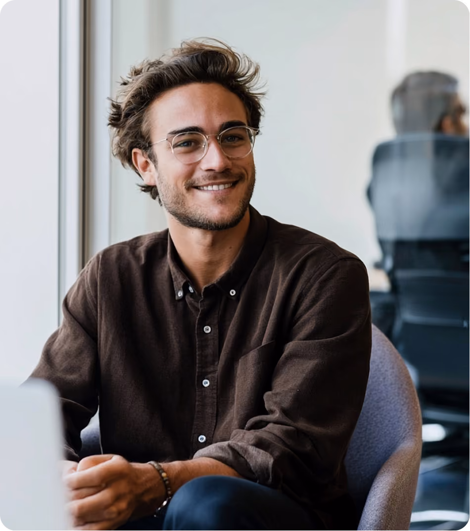 Un professionnel souriant à son poste de travail, dans un bureau partagé