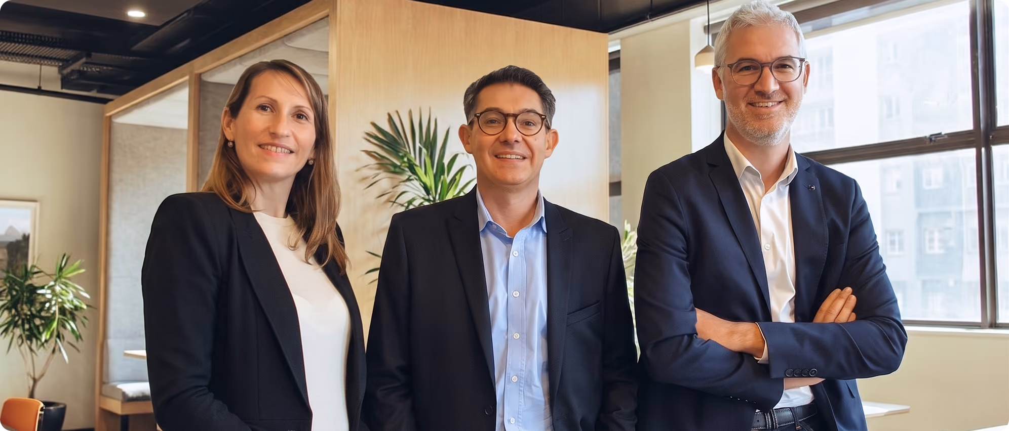 Trois professionnels souriants dans un espace de bureau