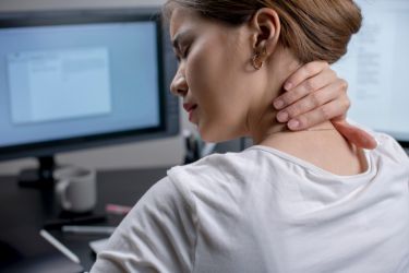 Woman with neck pain sitting in front of the computer