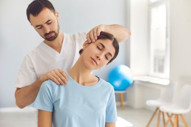 Woman with a male chiropractor helping her with her neck pain.
