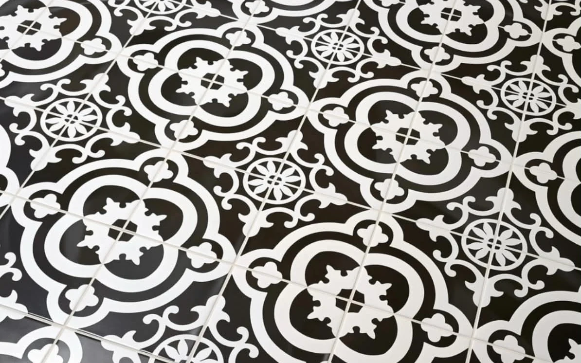 Black and white patterned encaustic tile floor, run tight to a wood threshold, installed by Euphoric Tile & Design in coastal Maine