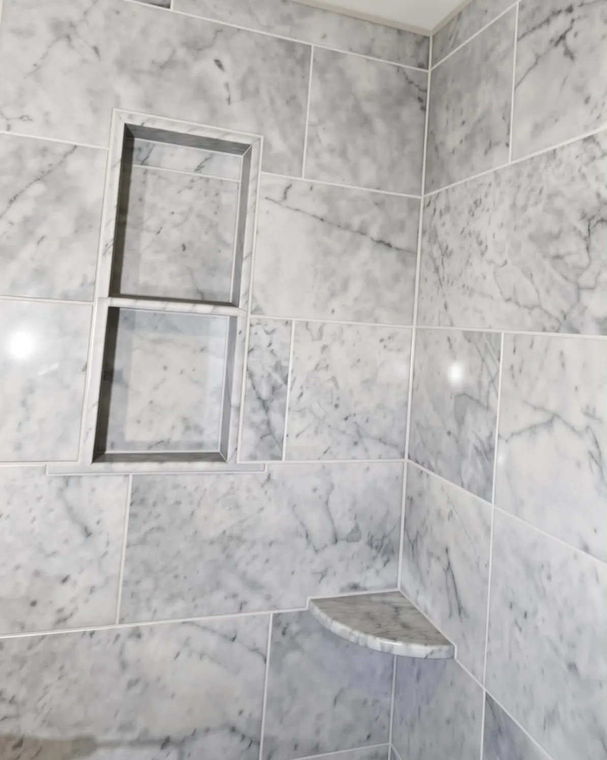 Carrara marble shower niche with twin shelves and tight joints, installed by Euphoric Tile & Design in coastal Maine