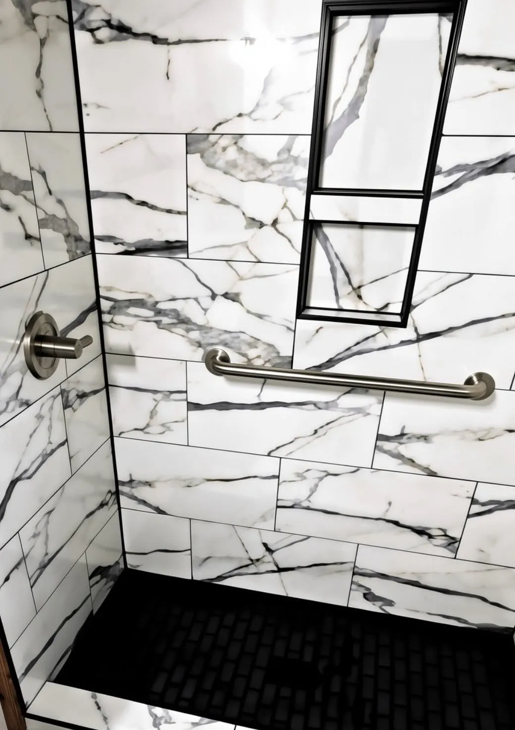 Calacatta marble shower with a black hexagonal mosaic pan and a framed niche, installed by Euphoric Tile & Design in coastal Maine
