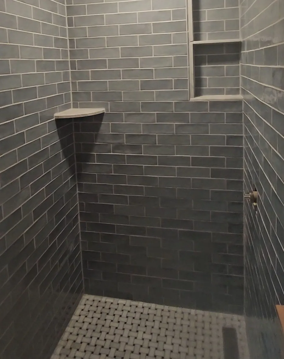 Charcoal subway tile shower with a corner shelf and a basketweave mosaic pan, installed by Euphoric Tile & Design in coastal Maine