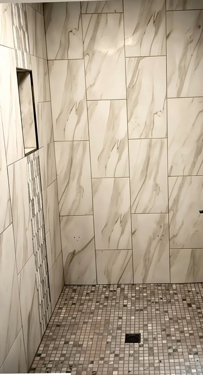Marble-look porcelain shower with a mosaic floor and a recessed niche, installed by Euphoric Tile & Design in coastal Maine