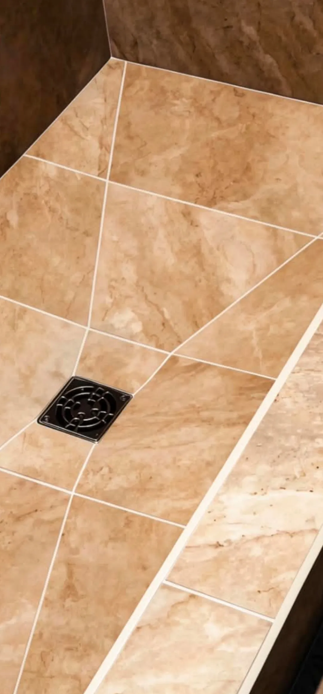 Travertine shower pan with a square drain, sloped to fall, installed by Euphoric Tile & Design in coastal Maine