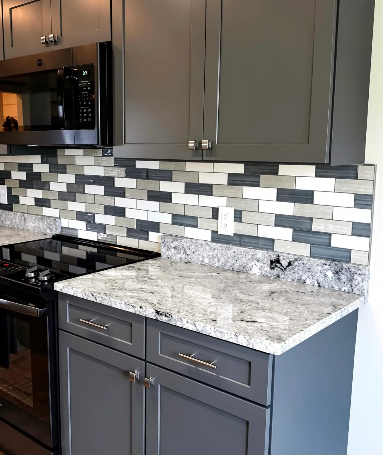 Glass tile kitchen backsplash set tight to a granite counter, installed by Euphoric Tile & Design in coastal Maine