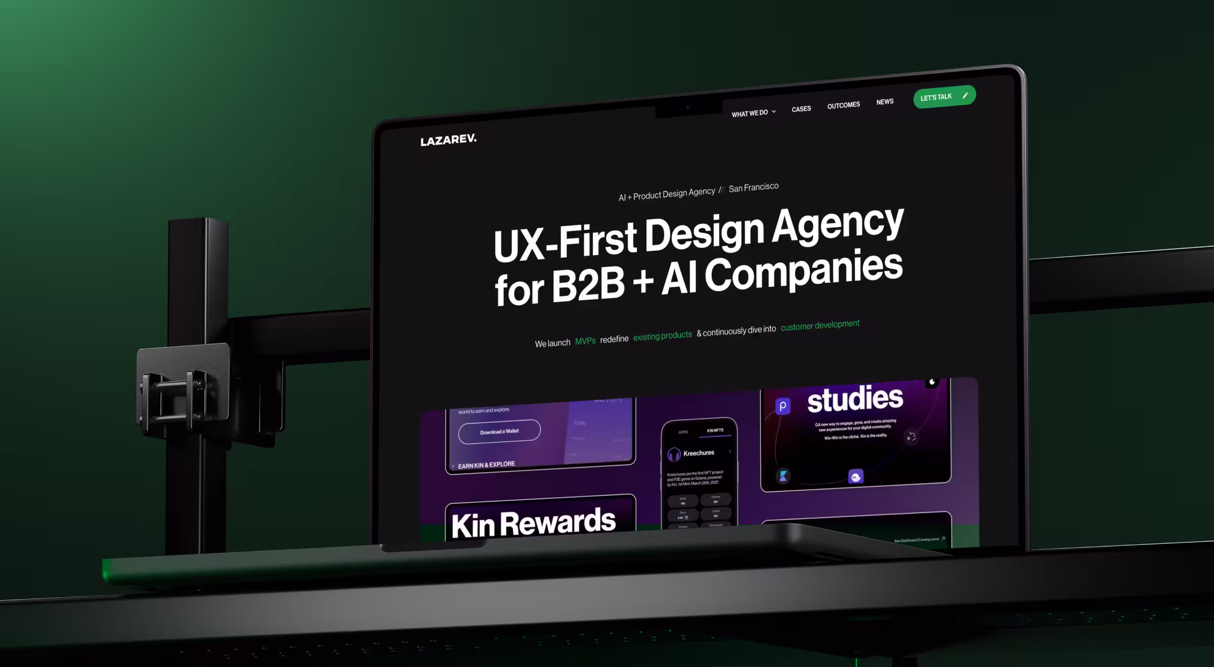 Laptop displaying the Lazarev.agency homepage with the headline ‘UX-First Design Agency for B2B + AI Companies,’ set against a dark green studio background with a metal monitor arm