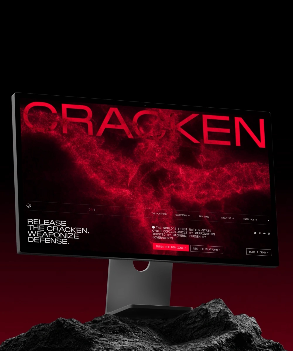 Cracken cybersecurity website hero displayed on a desktop monitor, using intense red visuals, dark rocky surroundings, and the headline “Release the Cracken. Weaponize defense.”