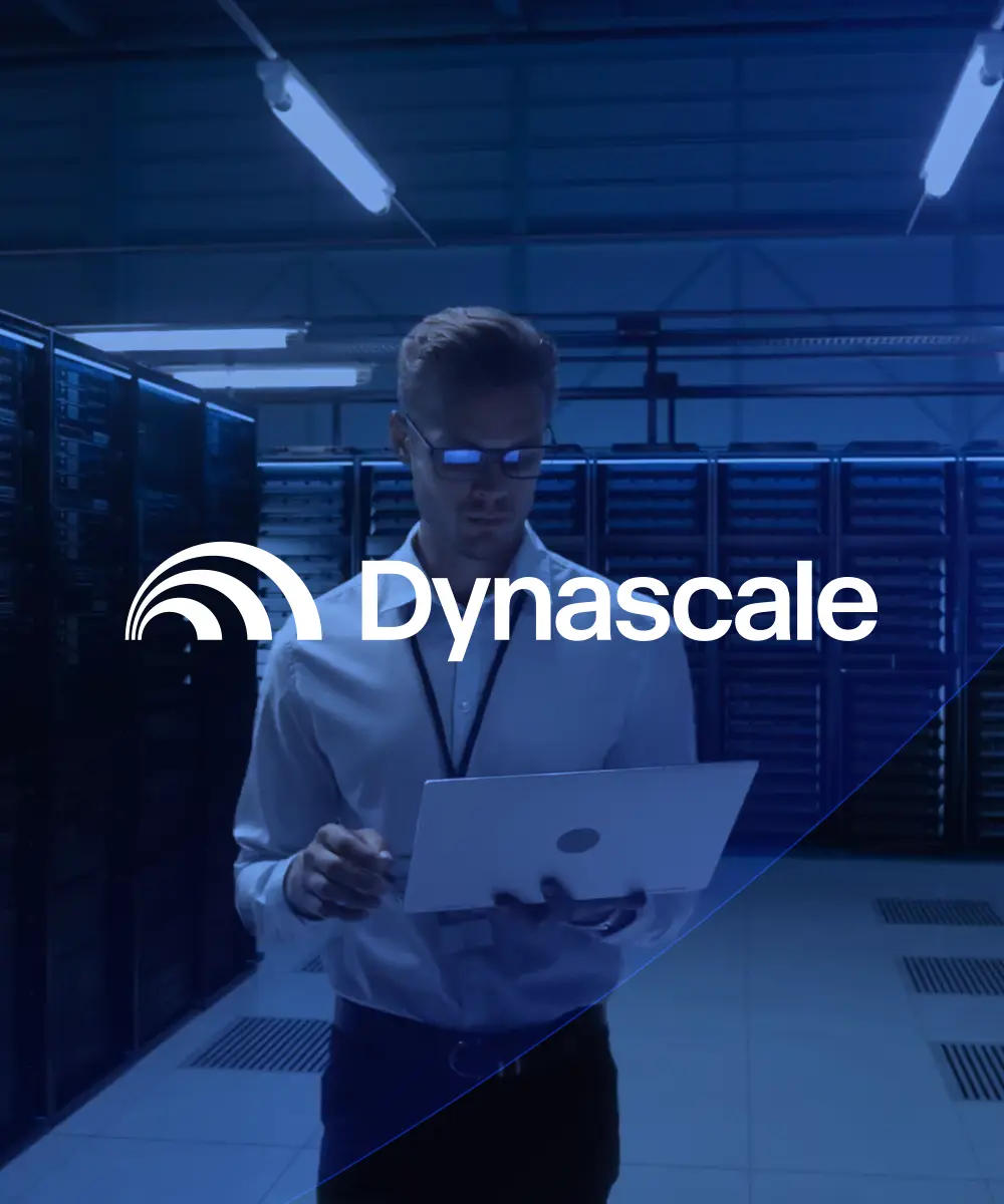 Dynascale branding visual: a technician holding a laptop in a blue-lit server room, with the "Dynascale" logo centered.