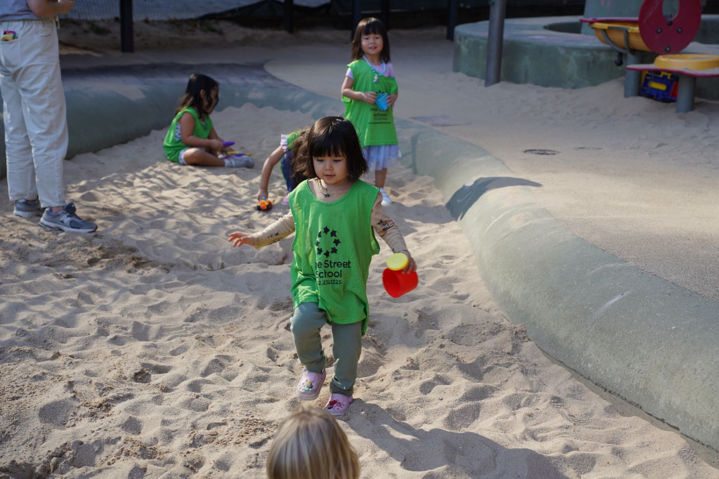 Three students playing in the sandbox during recess.