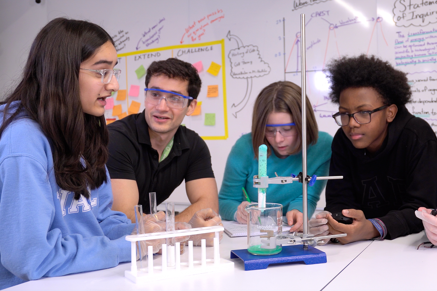 Four middle school students and their Science Teacher gather around the science experiment in the Middle School Science Lab at Pine Street School