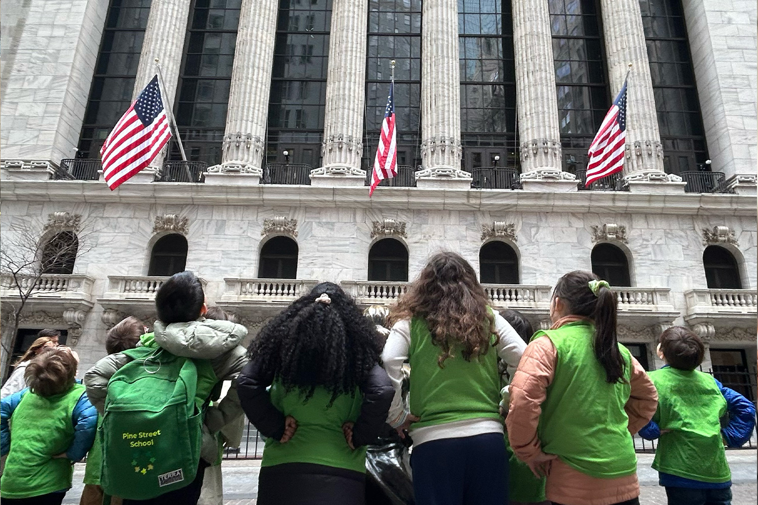 Pine Street School students looking up at the New York City Stock Exchange building during a field trip.