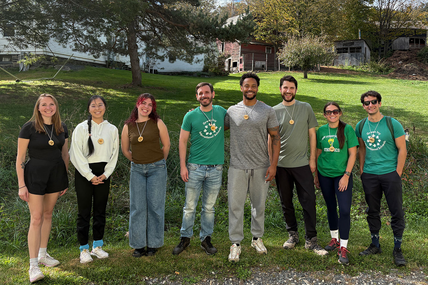 Group of Pine Street School teachers and staff posing on a grassy green field at Red Gate Farm.