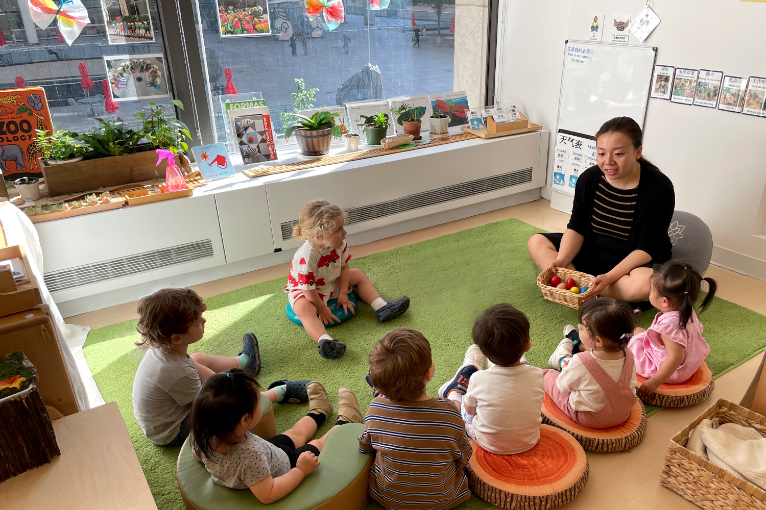 Trilingual Nursery students sitting in a circle in a classroom moment with their Mandarin teacher