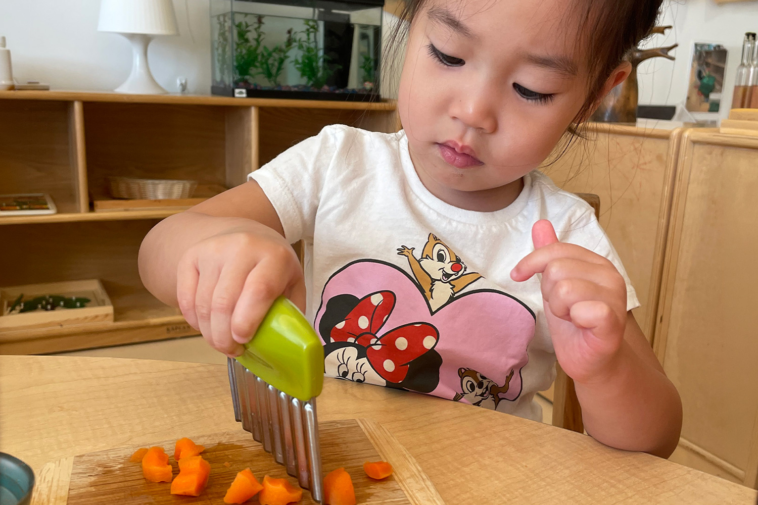 student cutting carrots on a cutting board as part of Pine Street School's Montessori program.