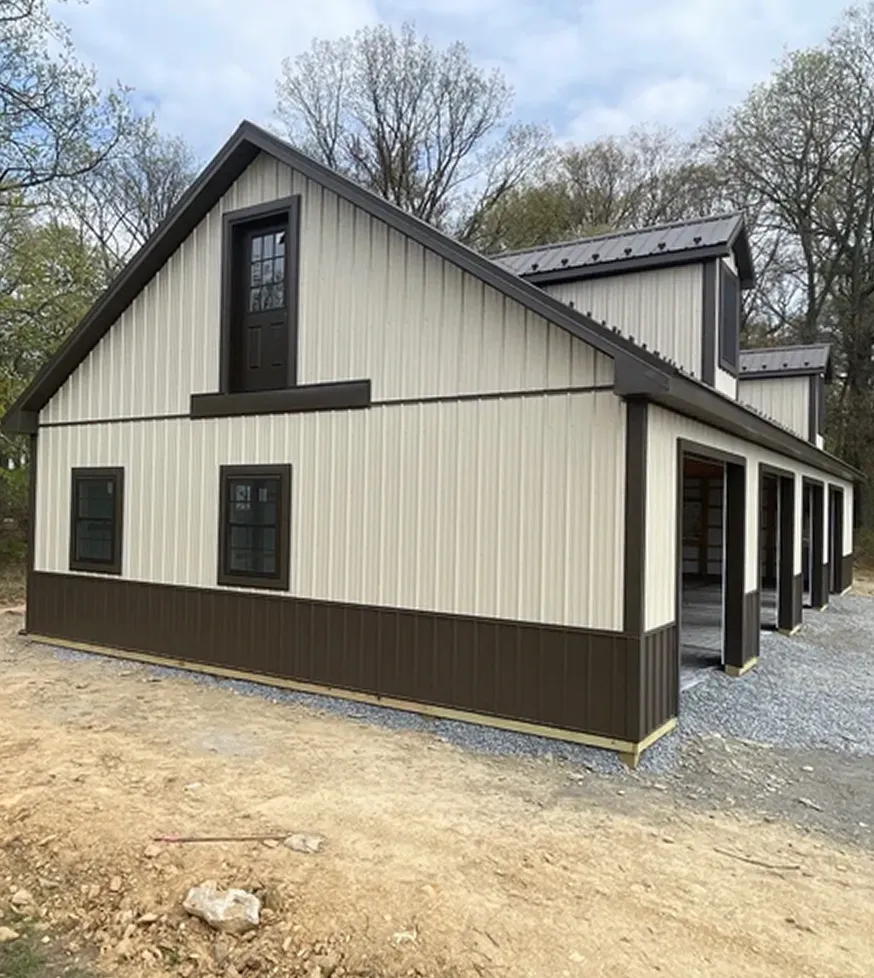 Two-tone metal barn with multiple large open garage doors and a door above one window.