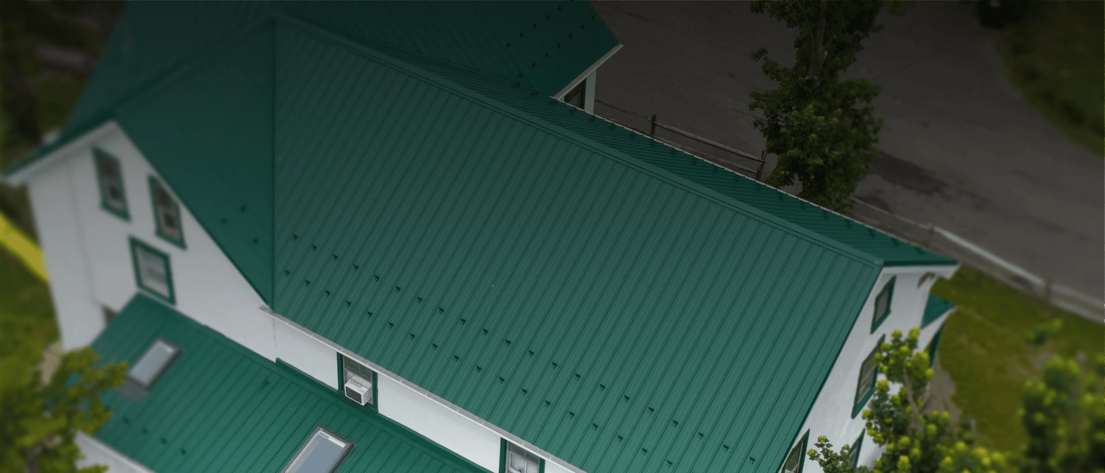 Aerial view of a white house with a green metal roof.