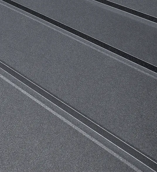 Close-up of dark gray textured metal roofing panels with raised seams.