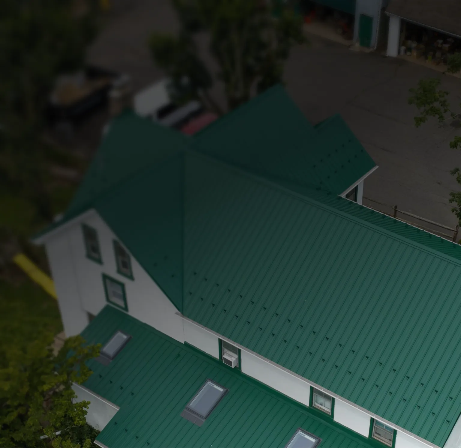 Aerial view of a white house with a green metal roof.