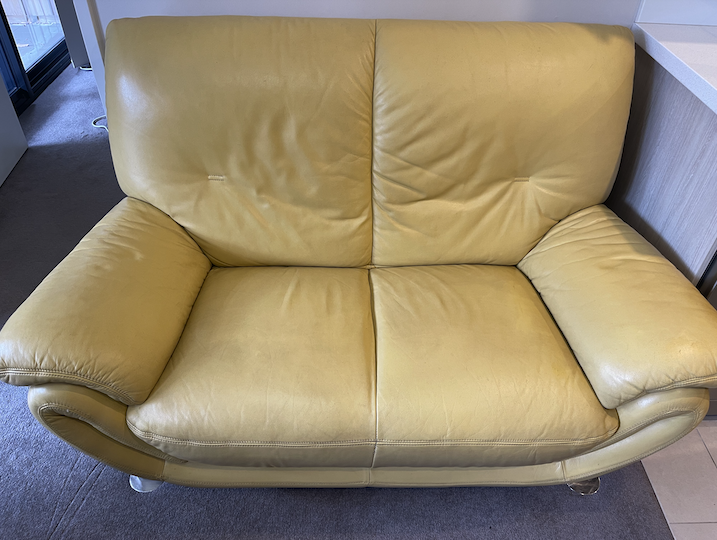 Mega Clean technician professionally cleaning a leather lounge