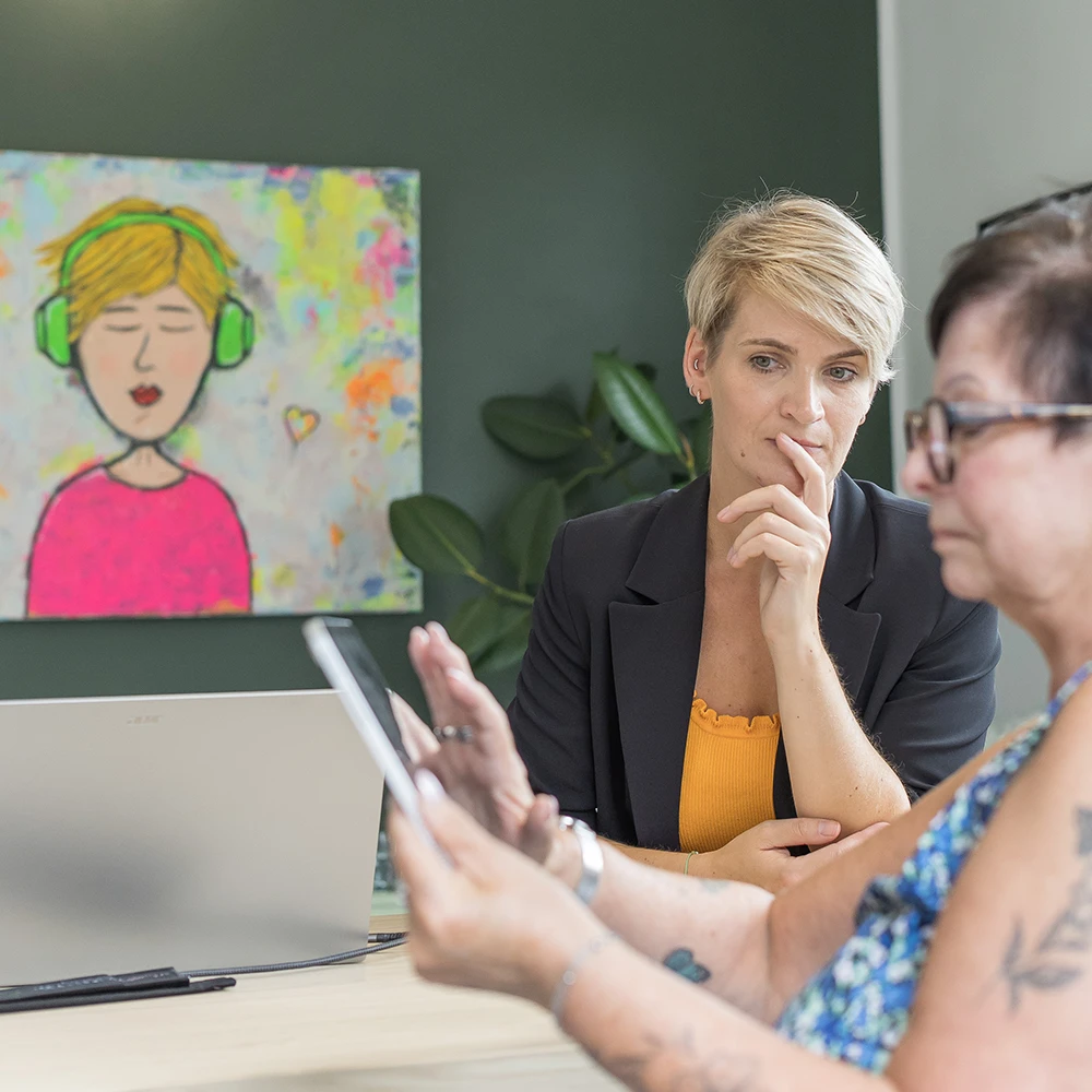 Frauen, die sich bei einem Treffen an einem Bildschirm einen Tablet-Bildschirm ansehen, im Büro.