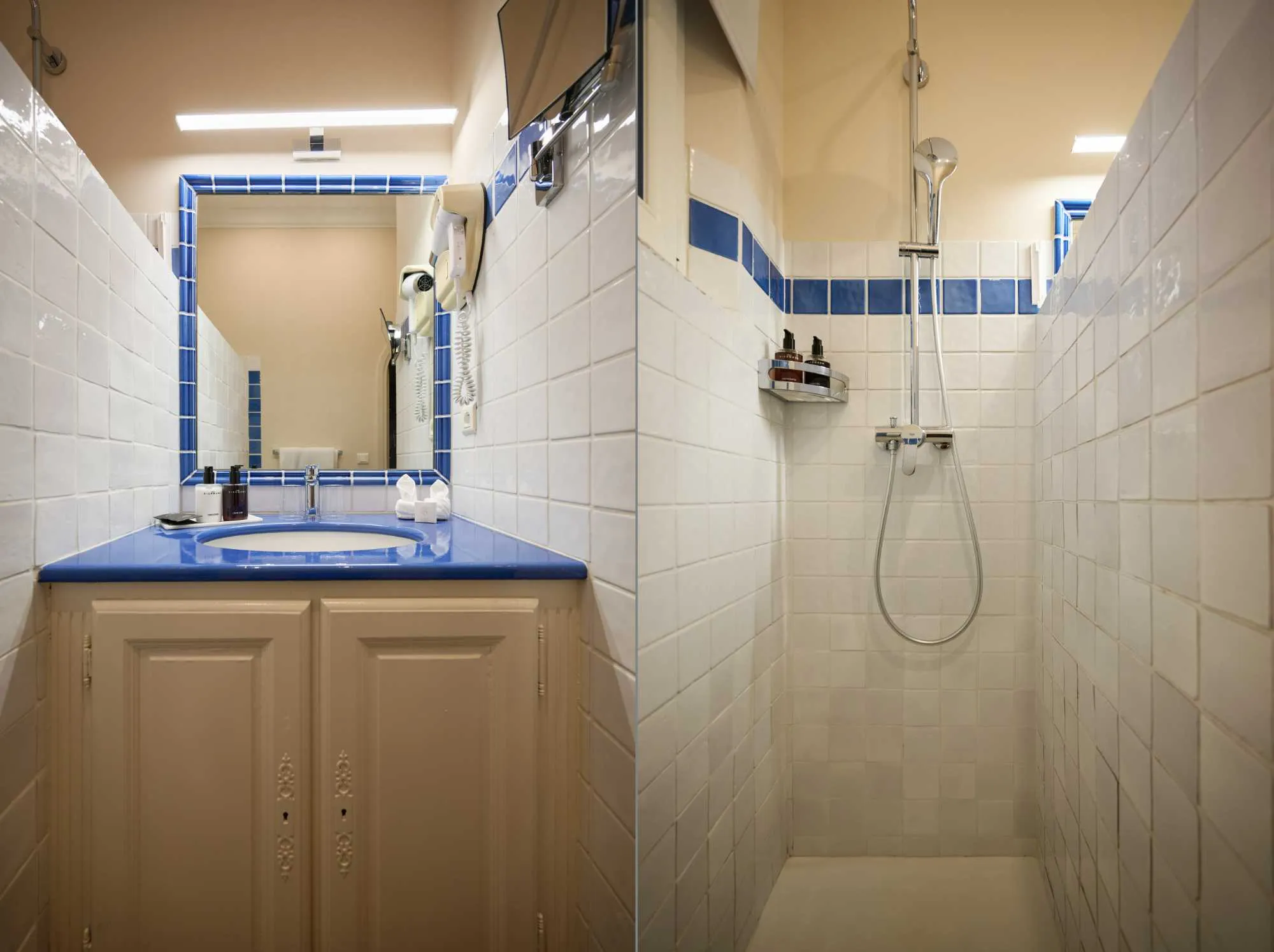 Deux vues d'une salle de bain provençale carrelée en blanc et bleu, avec vasque à plan bleu, meuble beige, et douche étroite au carrelage assorti.