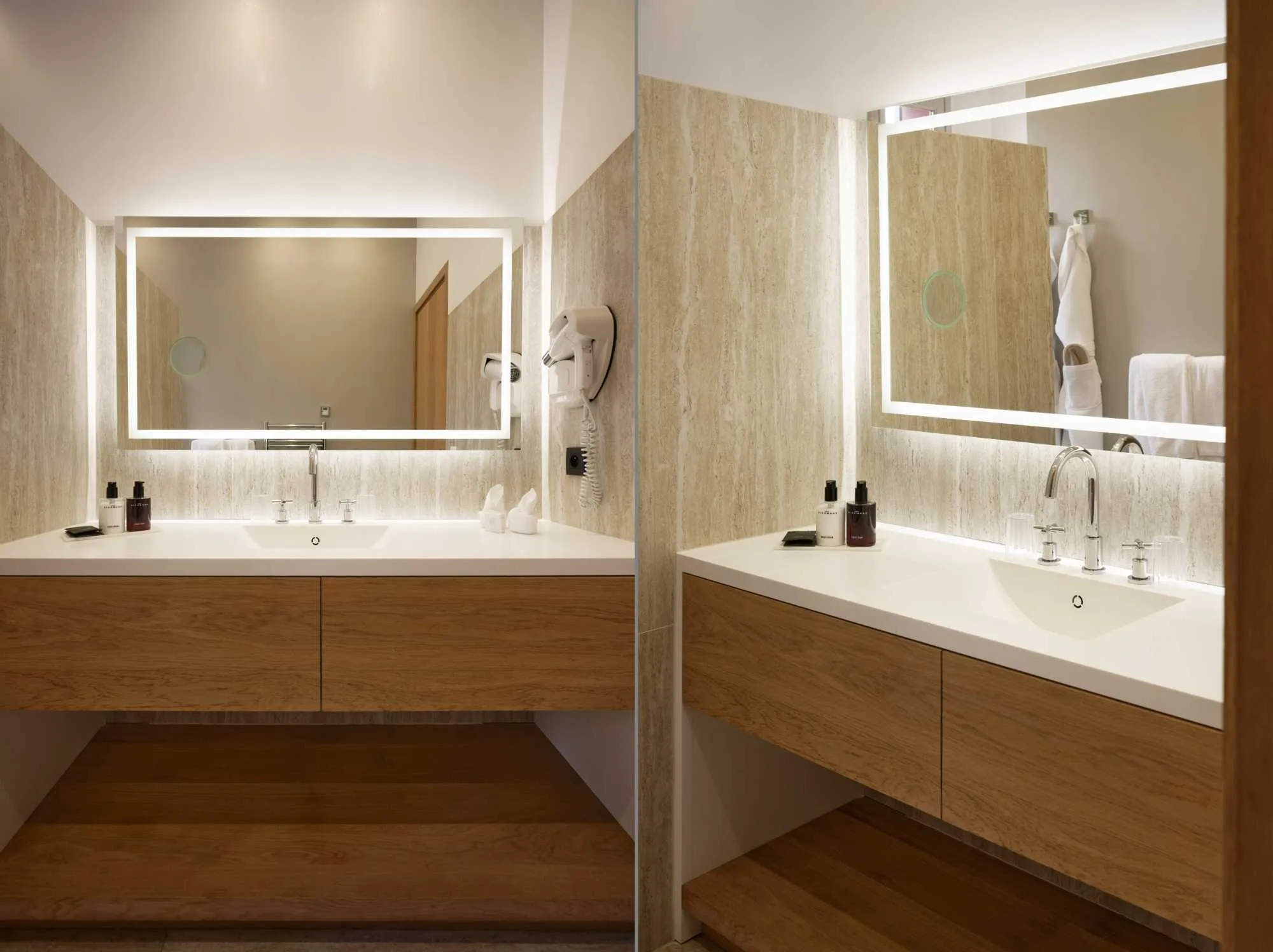 Deux vues d'une salle de bain moderne avec meubles vasque en bois, plan blanc, miroirs rétroéclairés et murs en marbre travertin.