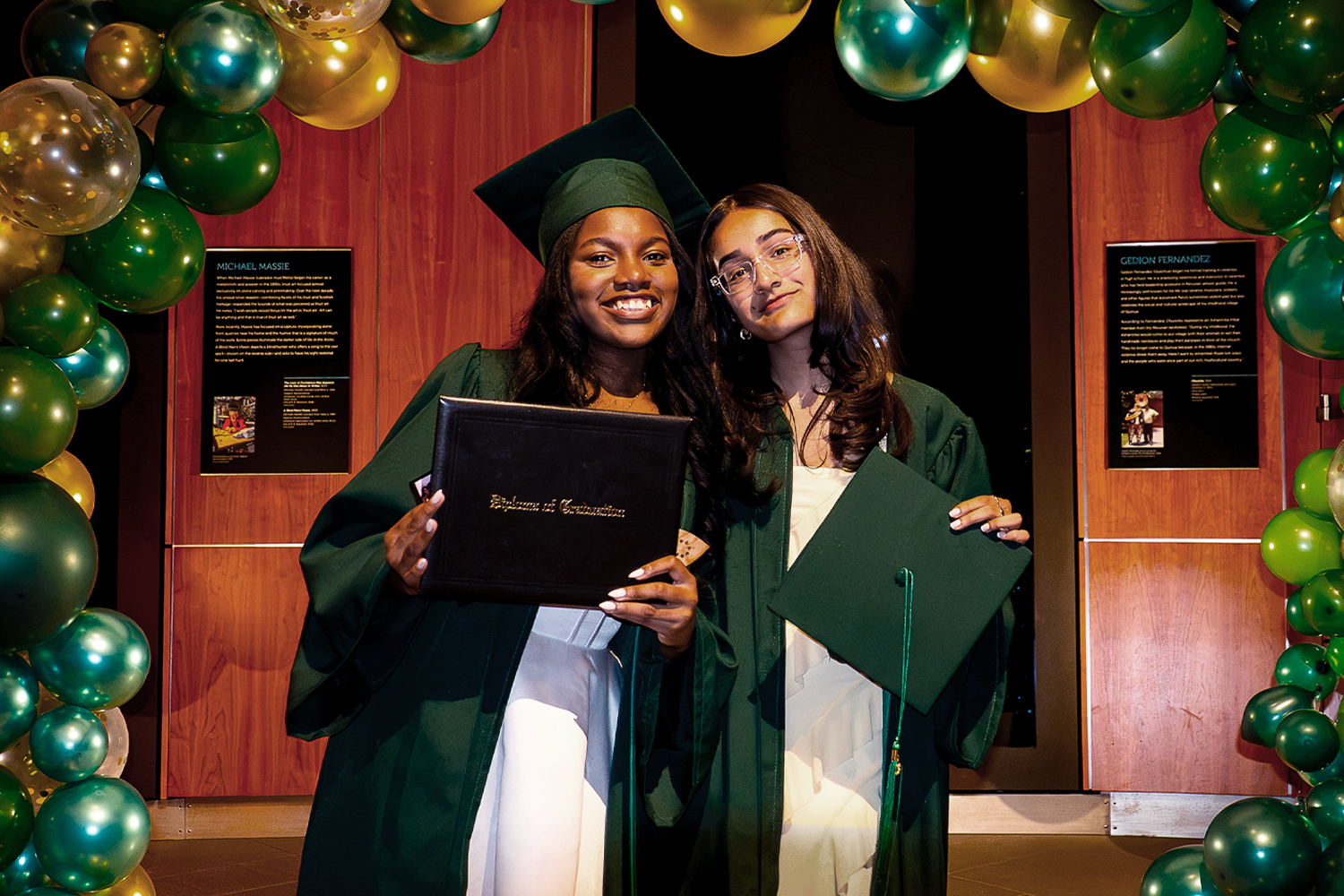 Two 8th grade students in cap and gown holding their graduation certificates at the Pine Street School Middle School Graduation Ceremony.