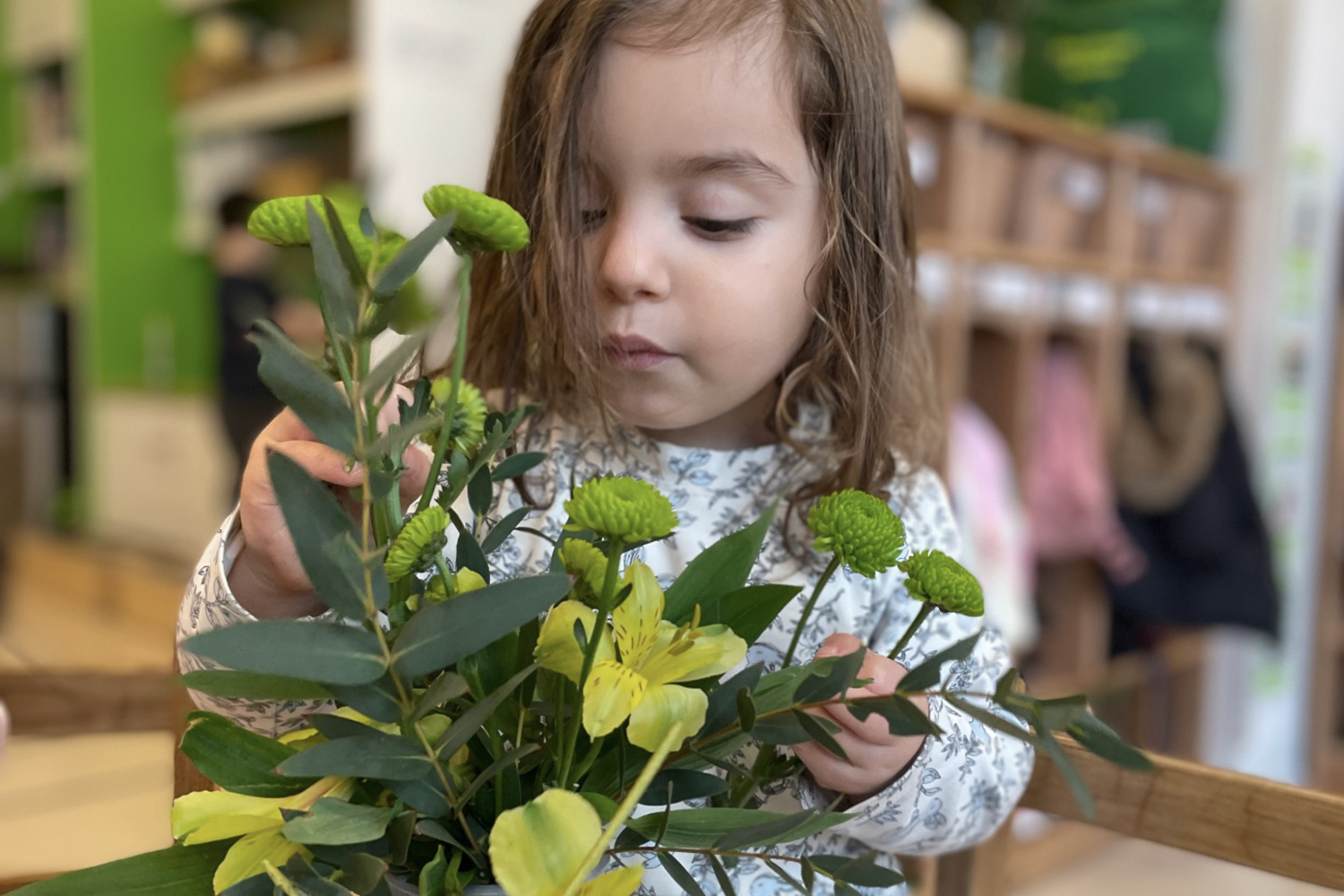 Pine Street School Nursery student engaged in a Montessori Practical Life activity, flower arranging, developing fine motor skills, concentration, and an appreciation for nature.