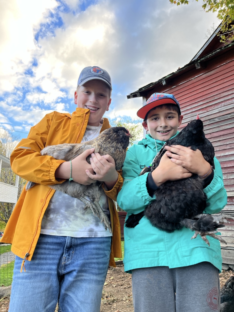 Two students holding chickens at the Red Gate Farm overnight trip