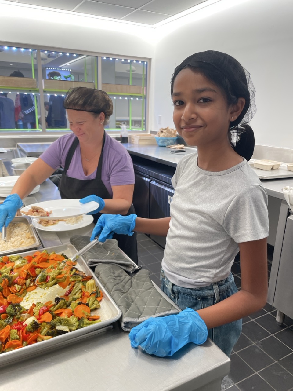Middle School student serving lunch alongside the staff