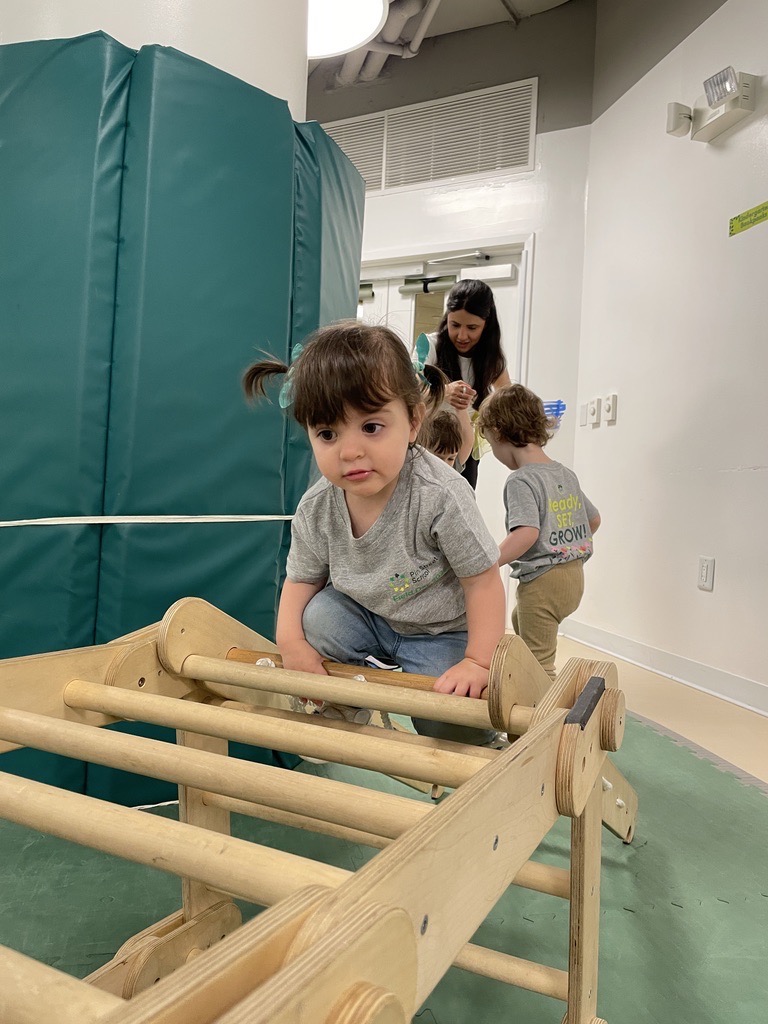 Nursery student climbs a Pikler triangle during movement time in the movement room.