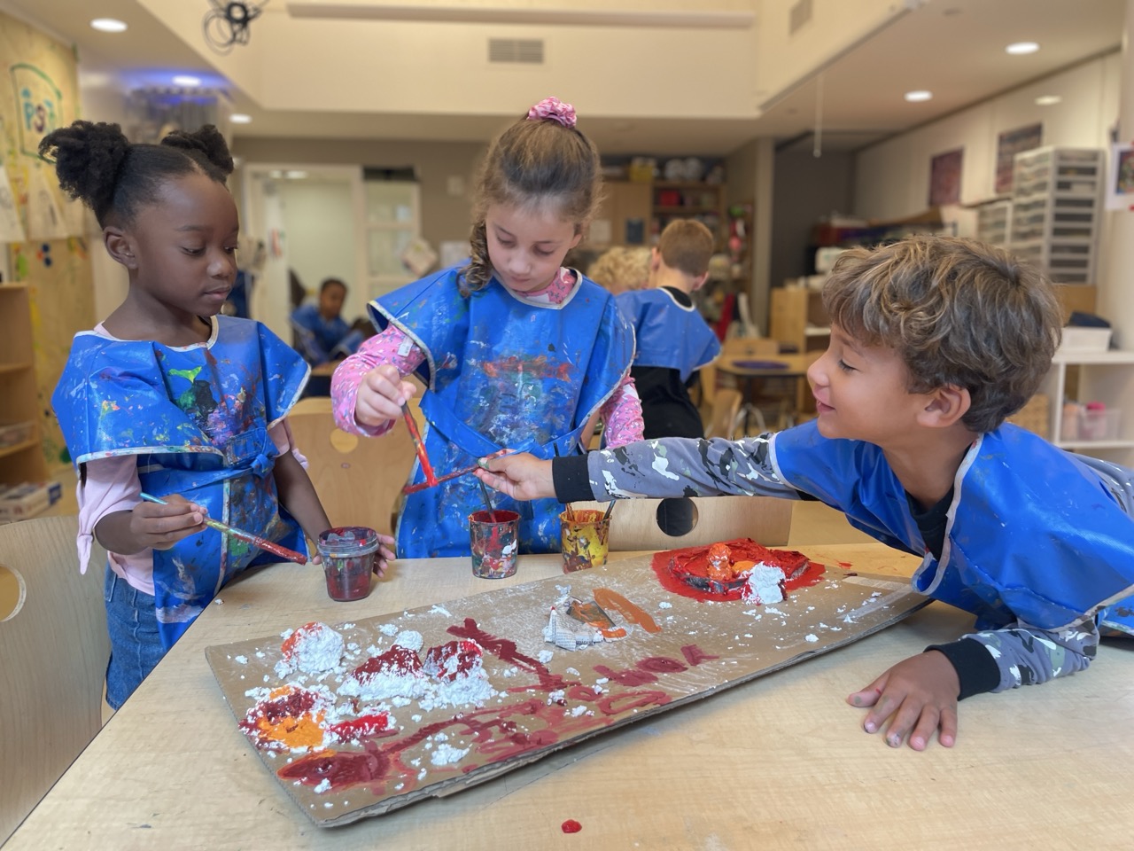 Students during art class creating a group piece using various colors of paint