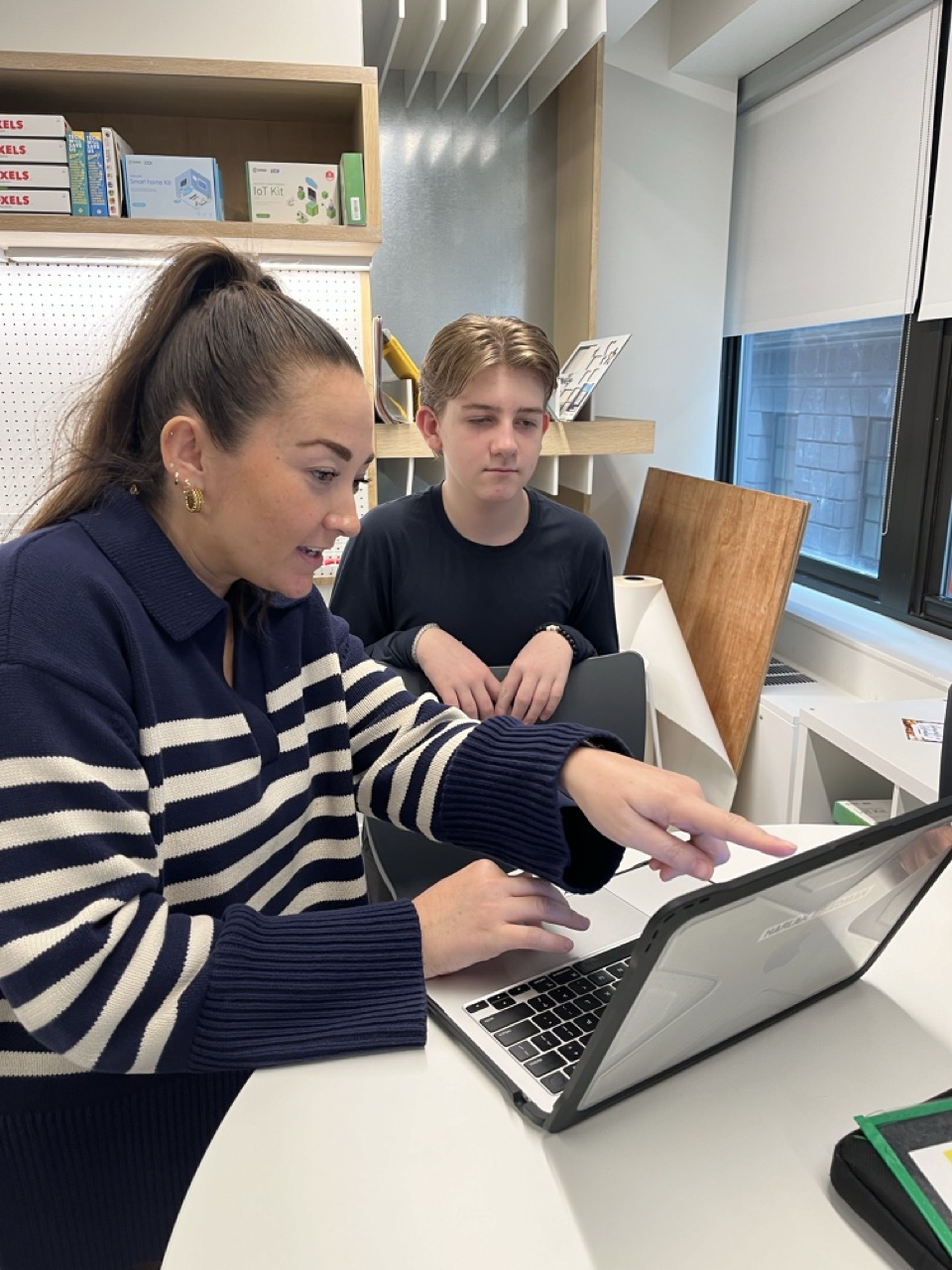 Head of Middle School points to a laptop screen with a middle school student