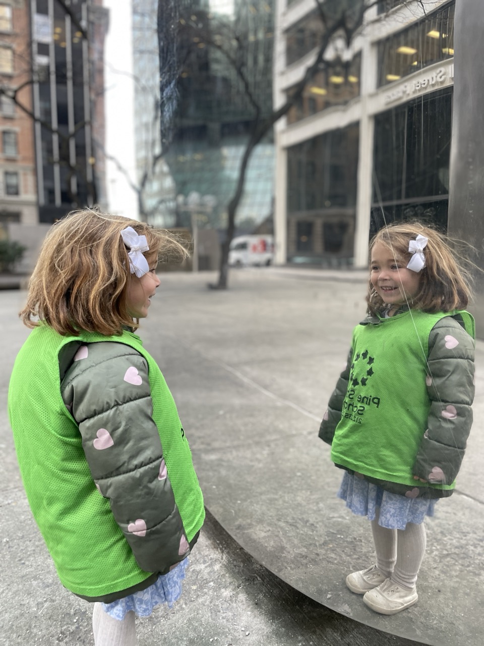 Student looking at her reflection in an outdoor mirrored sculpture.