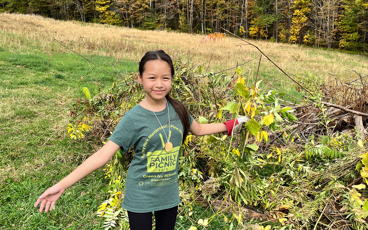 A student in front of a field and garden at Red Gate Farm