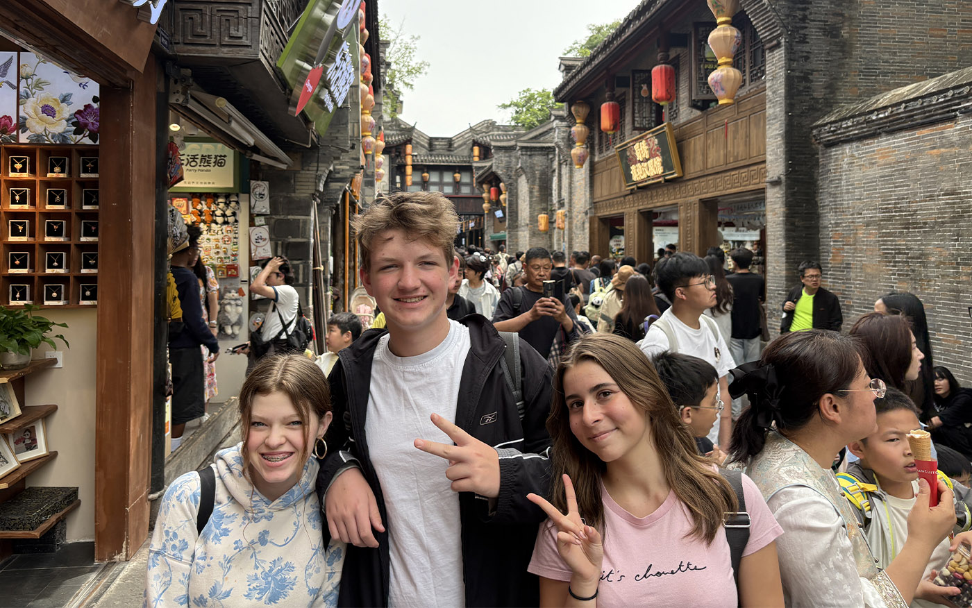 Three students smiling on a busy walking street in China